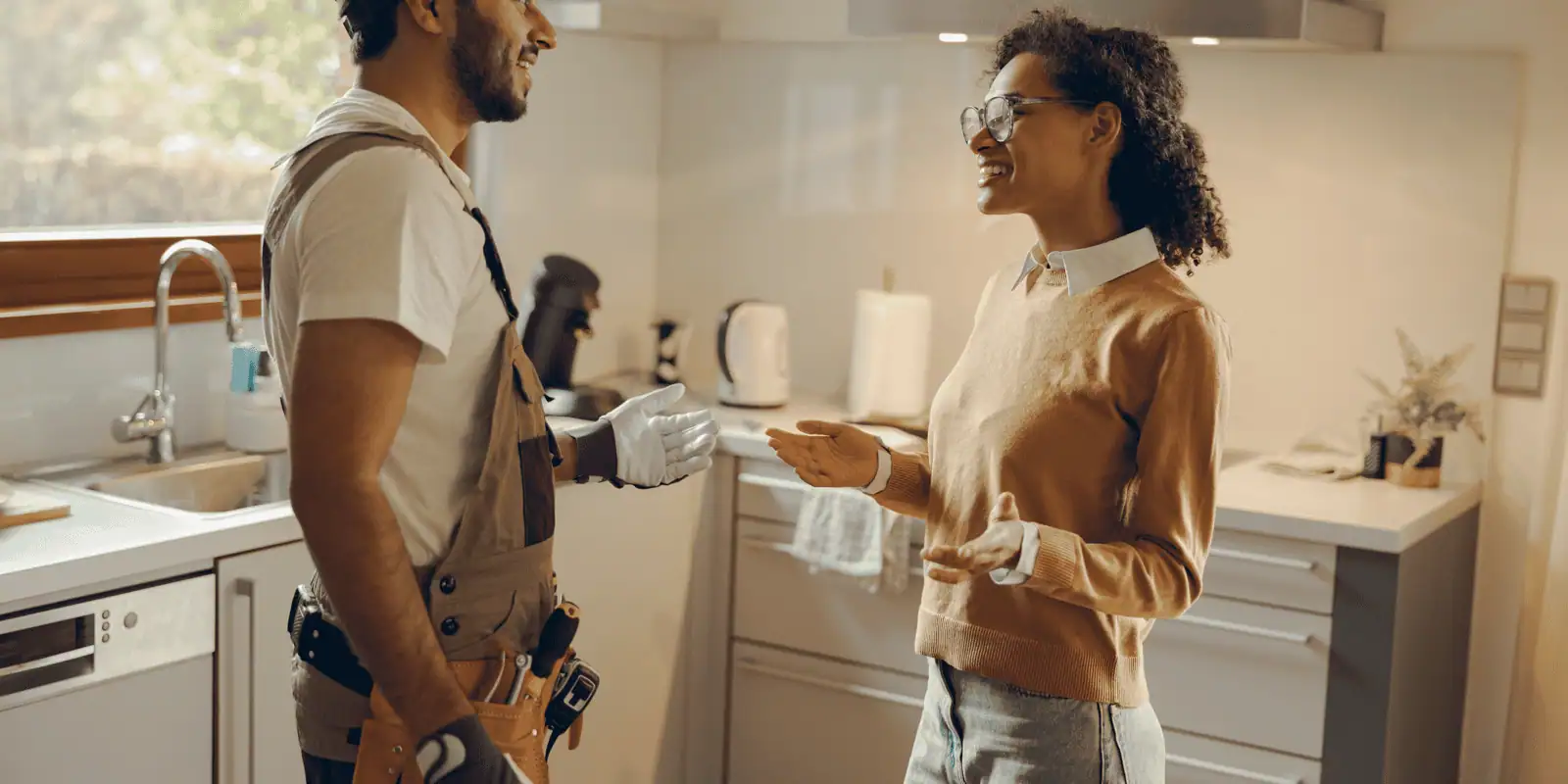 plumber and homeowner talking in kitchen